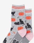 Two pairs of Halloween socks with black cats and pumpkins on a grey background