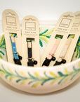 Cat collars in packaging displayed in a decorative bowl with floral patterns.