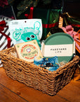 Wicker basket with pet care products including a cat toy and treats on a wooden floor.