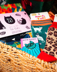 Cat-themed products including socks, tea towels, and cards in a basket.