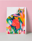 A cat greeting card with a colourful illustration of a cat blending various artistic styles, standing against a pink background.