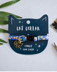 A black cat shaped tag with a blue and yellow floral patterned cat collar displayed on it, featuring a breakaway safety clasp with a design resembling a famous artist's style.