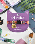 A colorful cat collar displayed on a card with the text 'CAT COLLAR' and 'WASSILY CATDINSKY'. The collar has a breakaway safety clasp and is surrounded by cat themed accessories and paint.