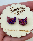 Purple cat-shaped earrings on a 'Esoteric London' branded card held in hand.