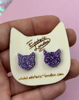 Purple glitter cat-shaped earrings on a wooden card with 'Esoteric London' branding.