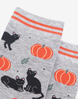 Halloween themed gray socks with orange pumpkins and black cats on a white background 