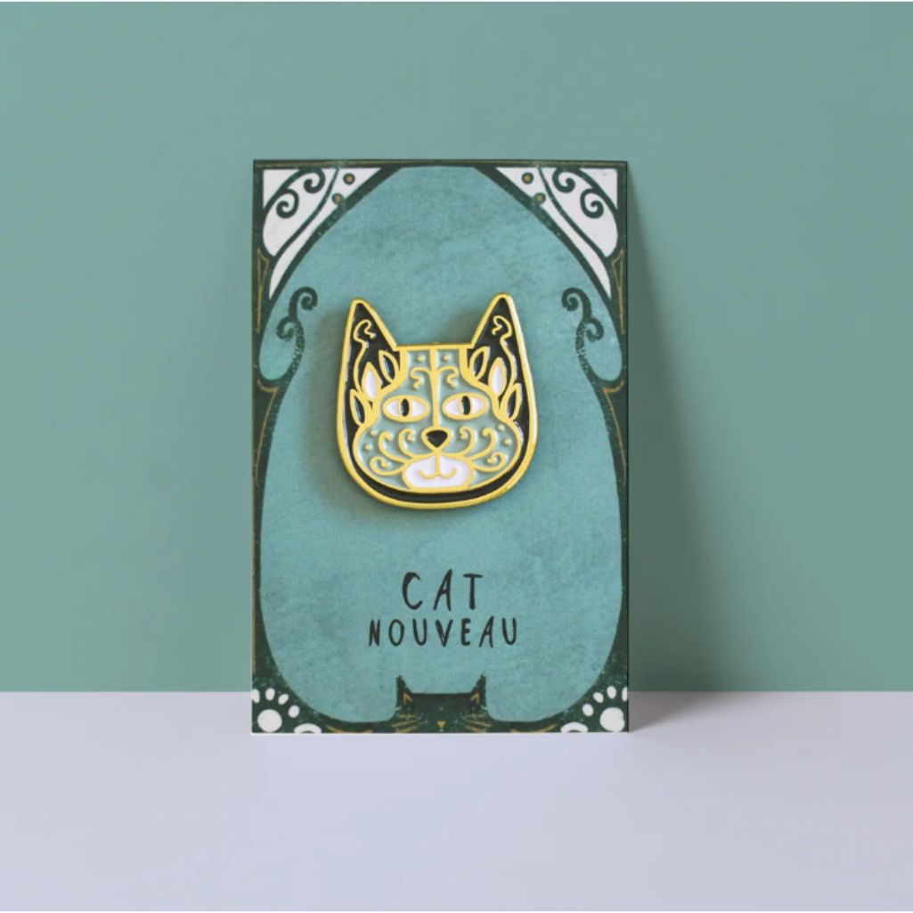 Card with a gold cat-shaped brooch on a teal background