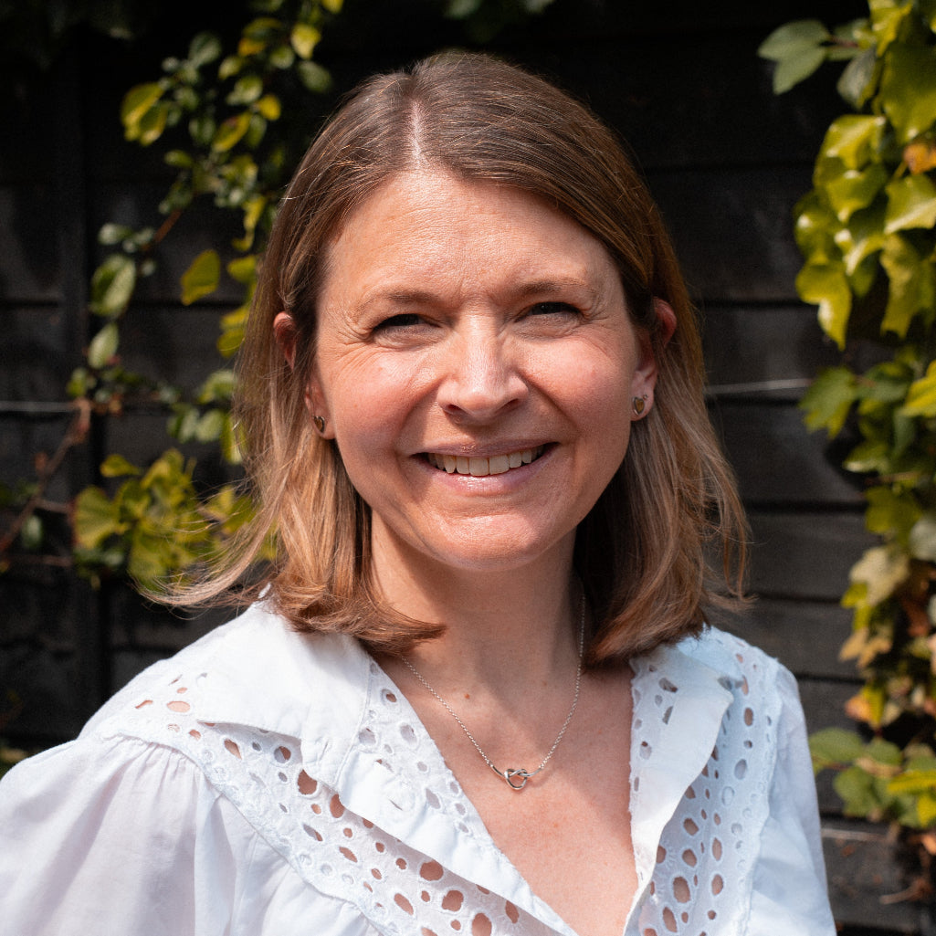 Woman wearing a white blouse with a blurred background of greenery