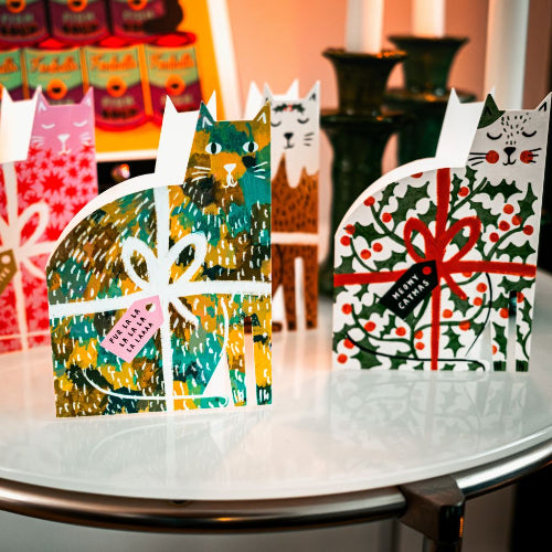 Decorative cat-shaped boxes with festive designs on a table.