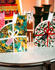Decorative cat-shaped boxes with festive designs on a table.