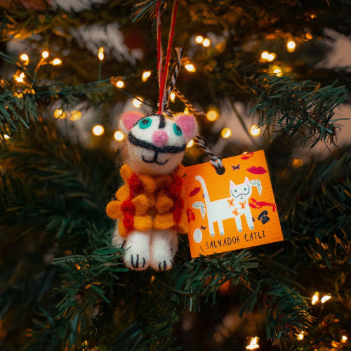 Cat-shaped ornament with an orange tag on a Christmas tree