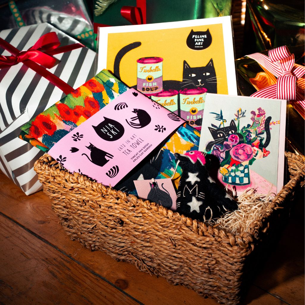 Basket of cat-themed greeting cards with colorful designs on a wooden surface.