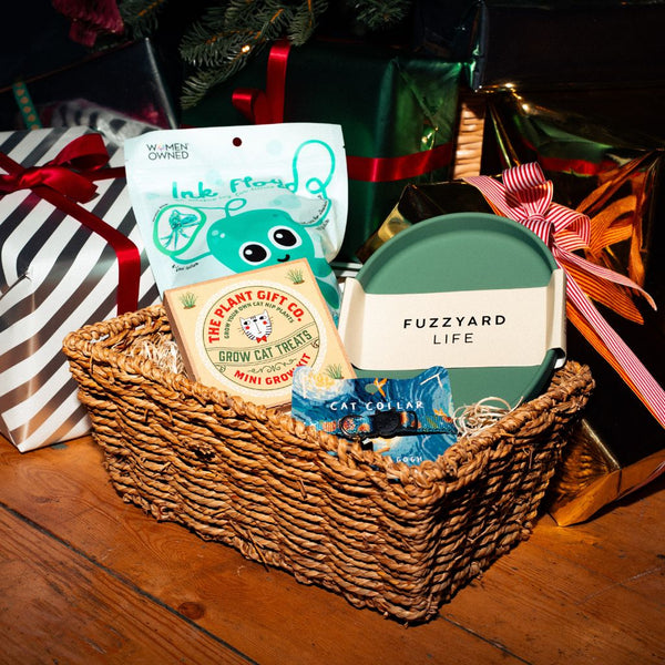 Wicker basket with pet care products including a cat toy and treats on a wooden floor.