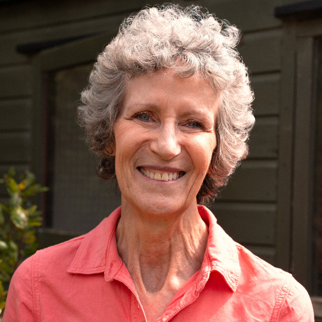 Woman with gray hair wearing a pink shirt outdoors