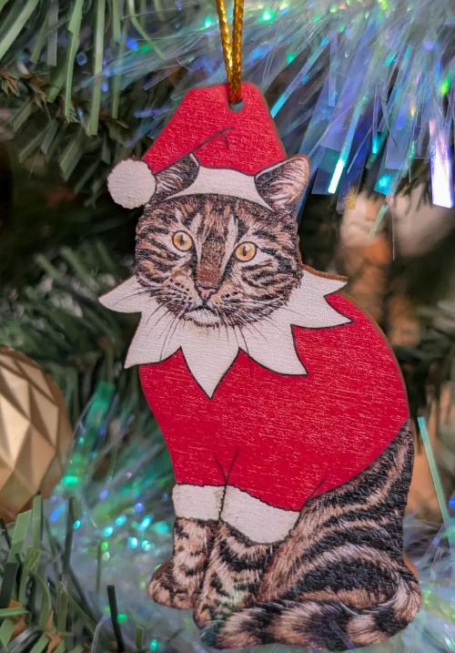 Cat Christmas ornament wearing a Santa hat and red outfit on a decorated tree.