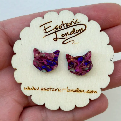 Purple cat-shaped earrings on a 'Esoteric London' branded card held in hand.