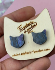 Cat-shaped earrings on a wooden display card held by a hand with 'Esoteric London' branding.