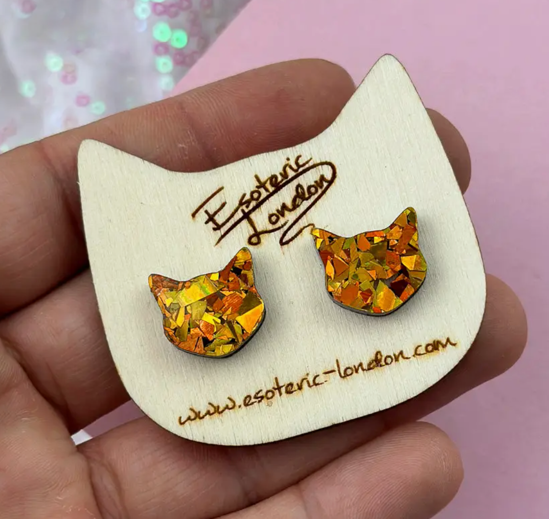 Cat-shaped earring card with orange glitter cat earrings on a pink background