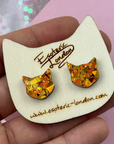 Cat-shaped earring card with orange glitter cat earrings on a pink background