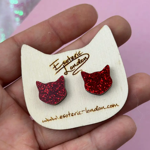 Red glitter cat ear-shaped earrings on a white card with &#39;Esoteric London&#39; branding.